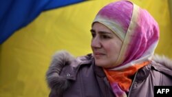 Ukraine - A Crimean Tatar woman stands by a Ukrainian flag as pro-Ukrainian demonstrators march in the streets of Simferopol in support of the Crimean Tatar community, on March 14, 2014