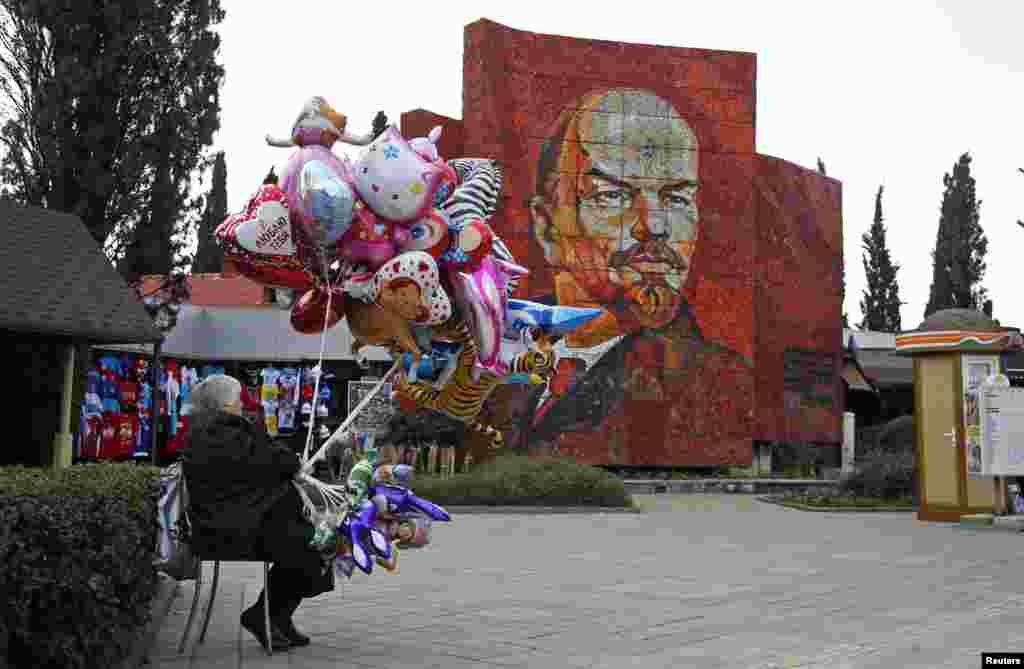 Жанчына прадае паветраныя шары перад партрэтам Леніна ў Сочы