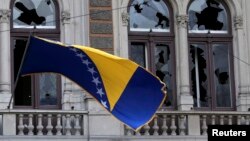 Bosnia-Herzegovina -- A Bosnian and Herzegovina national flag is seen on a damaged government building in Sarajevo February 8, 2014.