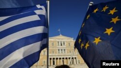 Greece -- Greece-EU-Eurozone-Debt-A woman waves a Greek national flag (L) and a European Union flag during a rally outside the parliament, in Athens June 18, 2015.